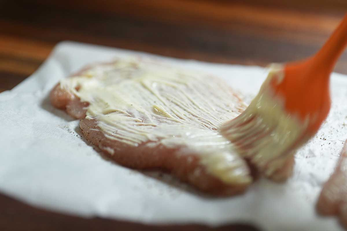 Spreading a very thin layer of garlic lemon mayo over the chicken cutlet