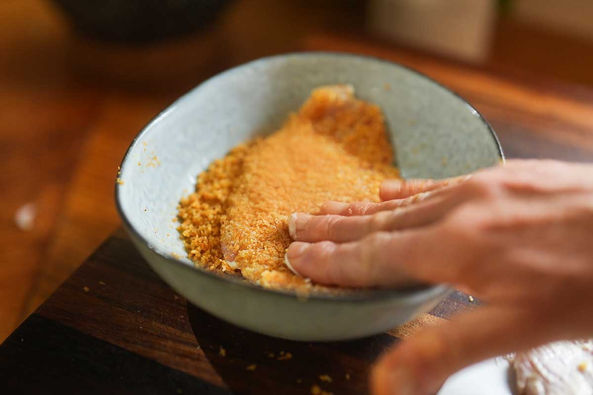 Pressing the cutlet firmly into the Parmesan panko mixture]