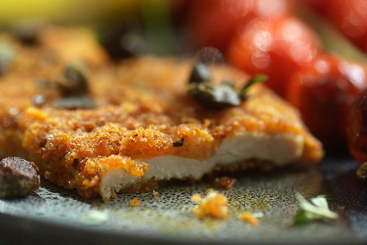 Close-up of a cutlet cut open, showing the crunchy crust and juicy chicken inside