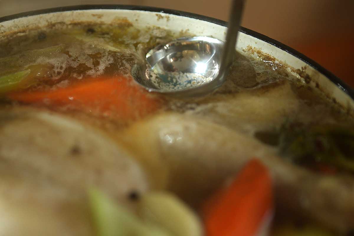 Skimming the foam off the surface of the gently poaching chicken