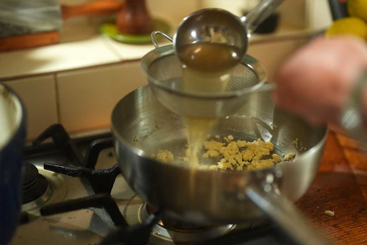 Straining the golden cooking liquid through a sieve