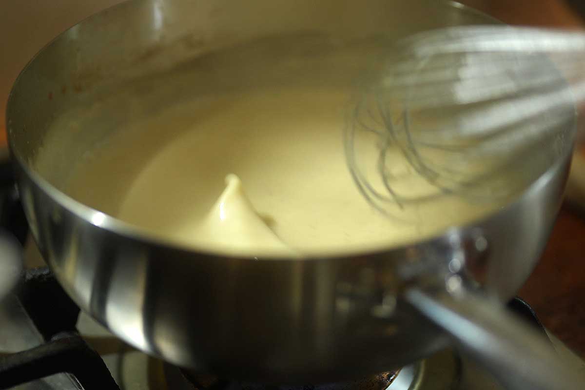Whisking the stock into the pale butter and flour roux to make the Dijon cream sauce